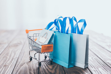 selective focus of toy shopping bags near small shopping trolley on wooden table