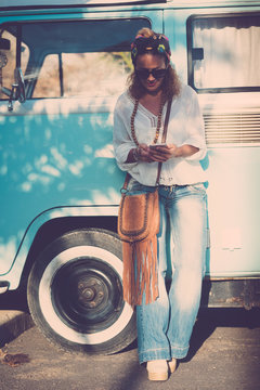trendy caucasian 40 years old woman smake a call with phone cell - fashion trend happy people outdoor enjoying lifestyle - old vintage bus blue in background - travel vacation alternative