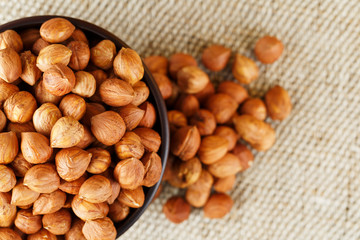 Peeled hazelnuts in a wooden, dark brown cup on a burlap cloth. Super Food, Raw.