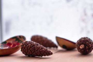 Wood spoon with three cones on wood table near the window