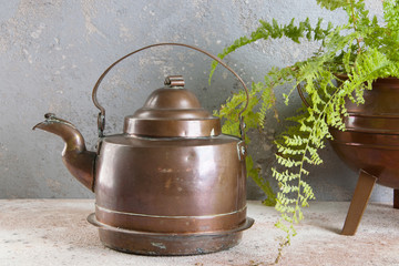 Vintage copper kettle on concrete background.
