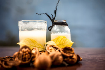 Close up of akhrot ka dudh or walnut milk on wooden surface with raw milk in  a glass bottle and some walnut in shell