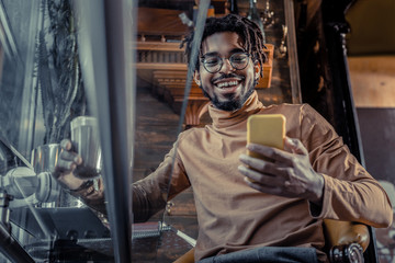 Positive delighted brunette man looking at his gadget