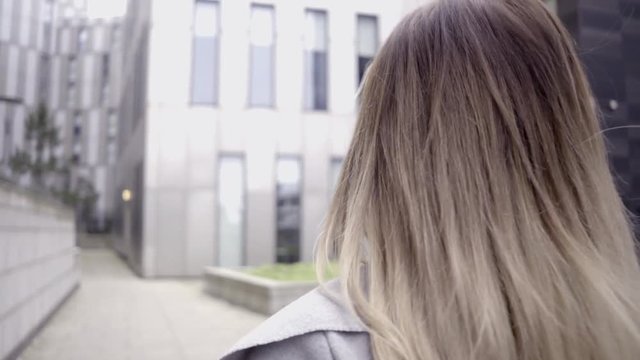 attractive blonde business woman confident grey coat walking city