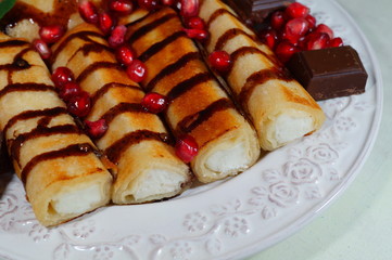 Pancakes with white cheese, chocolate sauce, whole grain granatas and chocolate cubes. Tasty appetizing dessert

