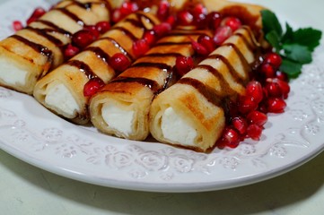 Pancakes with white cheese, chocolate sauce, whole grain granatas and chocolate cubes. Tasty appetizing dessert
