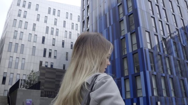 attractive blonde business woman confident grey coat walking city