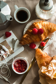 Kitchen table with french breakfast set. Freshly baked croissant, raspberry jam and coffee, blocnote, berries. Top view.