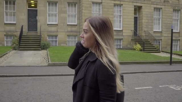 happy woman listening to music on headphones in front of old buildings
