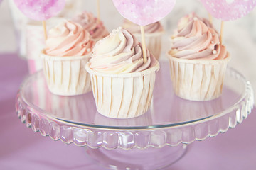 Tasty cupcakes on stand. Pink, purple background. Cupcakes with pink and white cream.