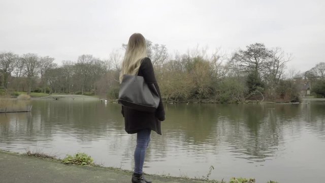 lonely woman looking at city lake winters day