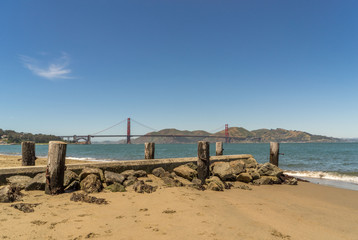 ramins of old wooden pier on the beach with Golden Gate bridge in background