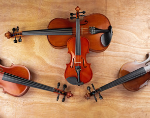 Fototapeta na wymiar The small size of violin put on the bigger size of violin,on wooden board,show texture and size of violin