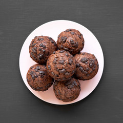 Chocolate cupcakes on pink plate on dark black surface, top view. Flat lay, overhead, from above.