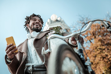 Delighted brunette man standing near his bicycle