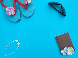 flat lay of sandal,passport,in-ear headphones on blue background with copy space