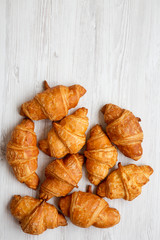 Freshly baked golden croissants on white wooden background, overhead view. Flat lay, from above, top view. Copy space.
