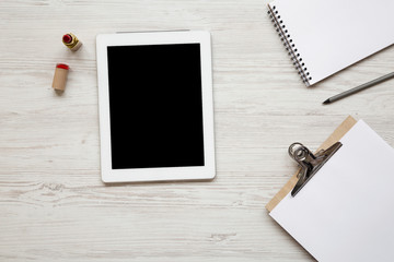 Feminine workspace with tablet, pencil, lipstick, notepad and clipboard, overhead view. Flat lay, from above, top view.