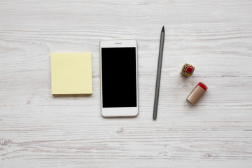 Feminine workspace with lipstick, smartphone, pencil and stickers, top view. Flat lay, overhead, from above.