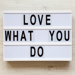 Modern board with text 'Love what you do' over white wooden surface, top view. Business concept. From above, flat lay, overhead.
