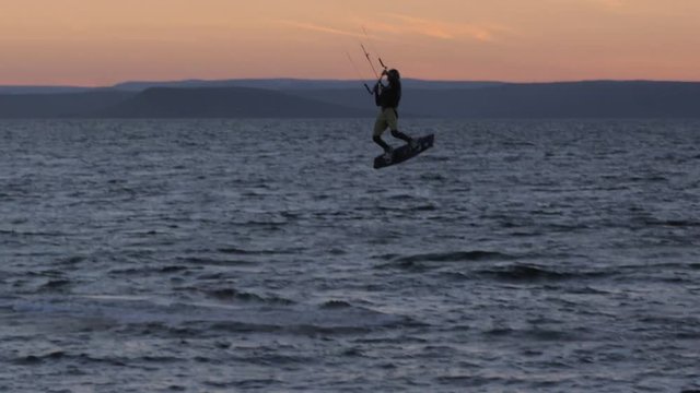Kite-surfing against a beautiful sunset. Silhouette of kitesurfer. Holidays on nature. Artistic picture.