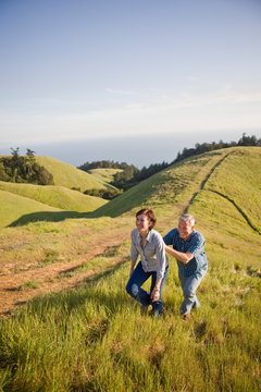 Happy mid-adult couple walking together through a remote grassy field in the country.