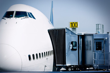 Moveable boarding corridor attached to the side of a large passenger plane at an airport.
