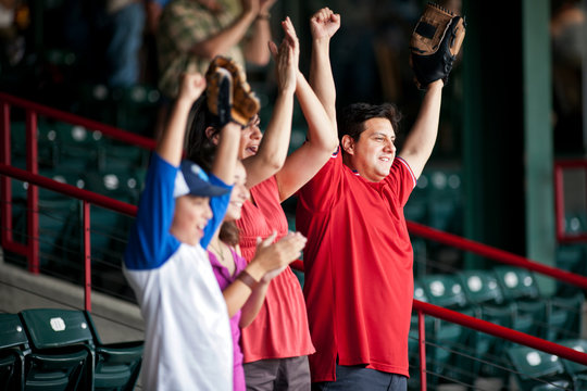 Family cheering on a baseball game at a sports stadium.