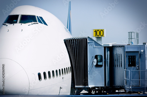 Moveable boarding corridor attached to the side of a large passenger plane at an airport.