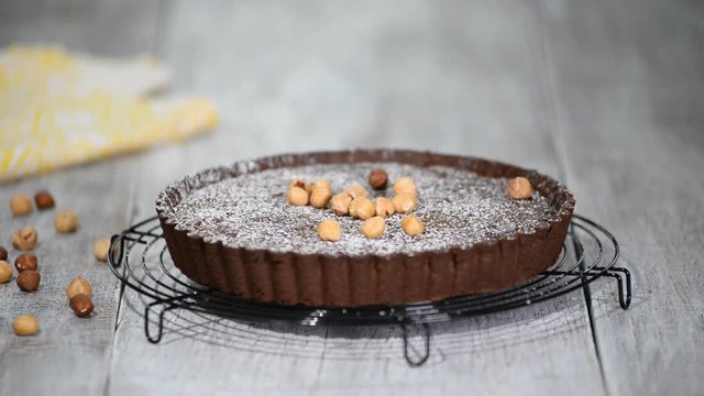 Chocolate tart with hazelnut on a plate on the table.