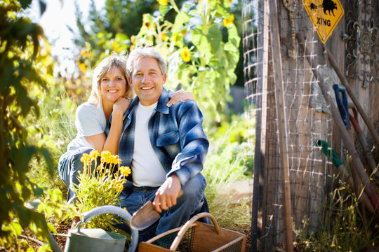 Portrait of a smiling mid-adult couple sitting in their garden in the sunshine.
