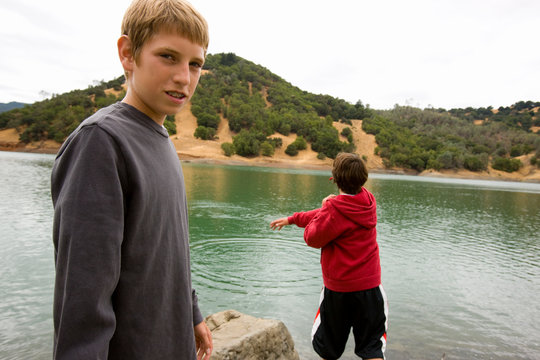 Portrait of two boys standing next to a lake.