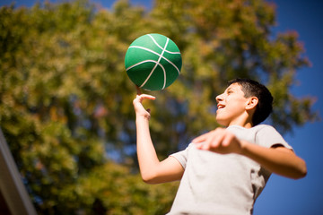 Teenage boy spinning basketball on one finger