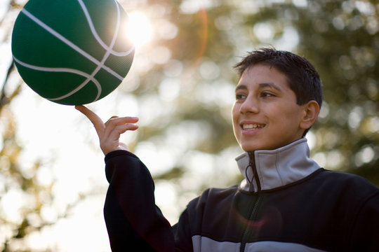 Teenage boy spinning basketball on one finger