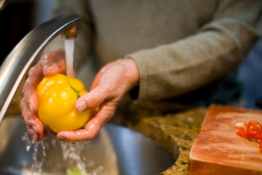 Older woman washing yellow bell pepper - Powered by Adobe