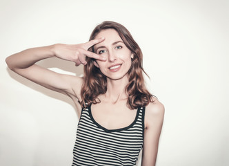 Fototapeta premium Nice girl in a striped T-shirt. Fingers gesture v
