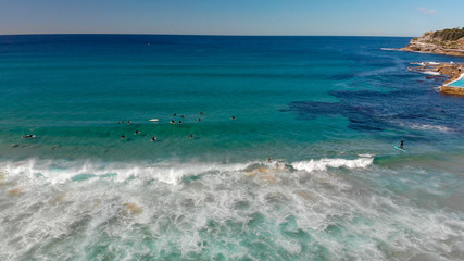 Fototapeta na wymiar Aerial view of Bondi Beach coastline with surfers and waves, Sydney, Australia.