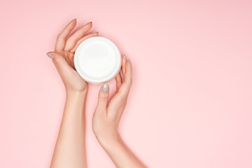 cropped of view of female hands with body cream isolated on pink with copy space