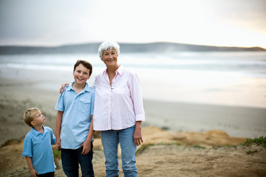 Grandmother and two grandsons pose for a portrait at the beach.
