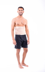 shirtless man in studio with white background wearing orthopedic corset