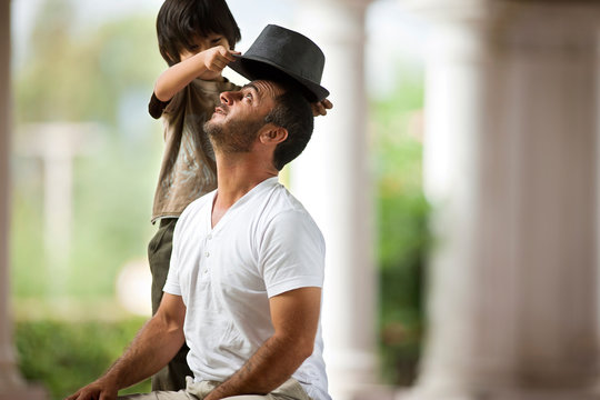Boy playing with his fathers hat.
