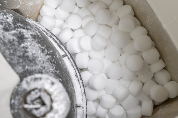 Salt pellets lies in water softener. Close-up.