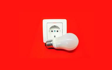 bulb and electrical outlet on isolated red background