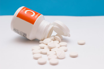 Vitamin C bottle with tablets on blue background