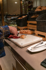 Fototapeta na wymiar Vertical photo of woman hand cutting bread with a knife