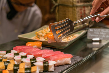 Girl hand choosing Salmon sushi in the buffet
