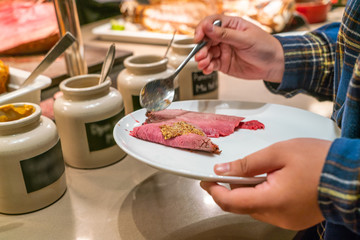 Woman hand taking food in the restaurant buffet