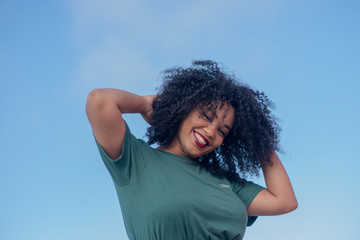 Fototapeta na wymiar Smiling woman with curly hair against blue sky