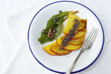 Sliced yellow beet carpaccio with mustard and capers.