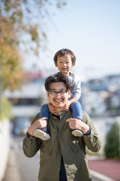 Portrait of smiling father carrying son on shoulder